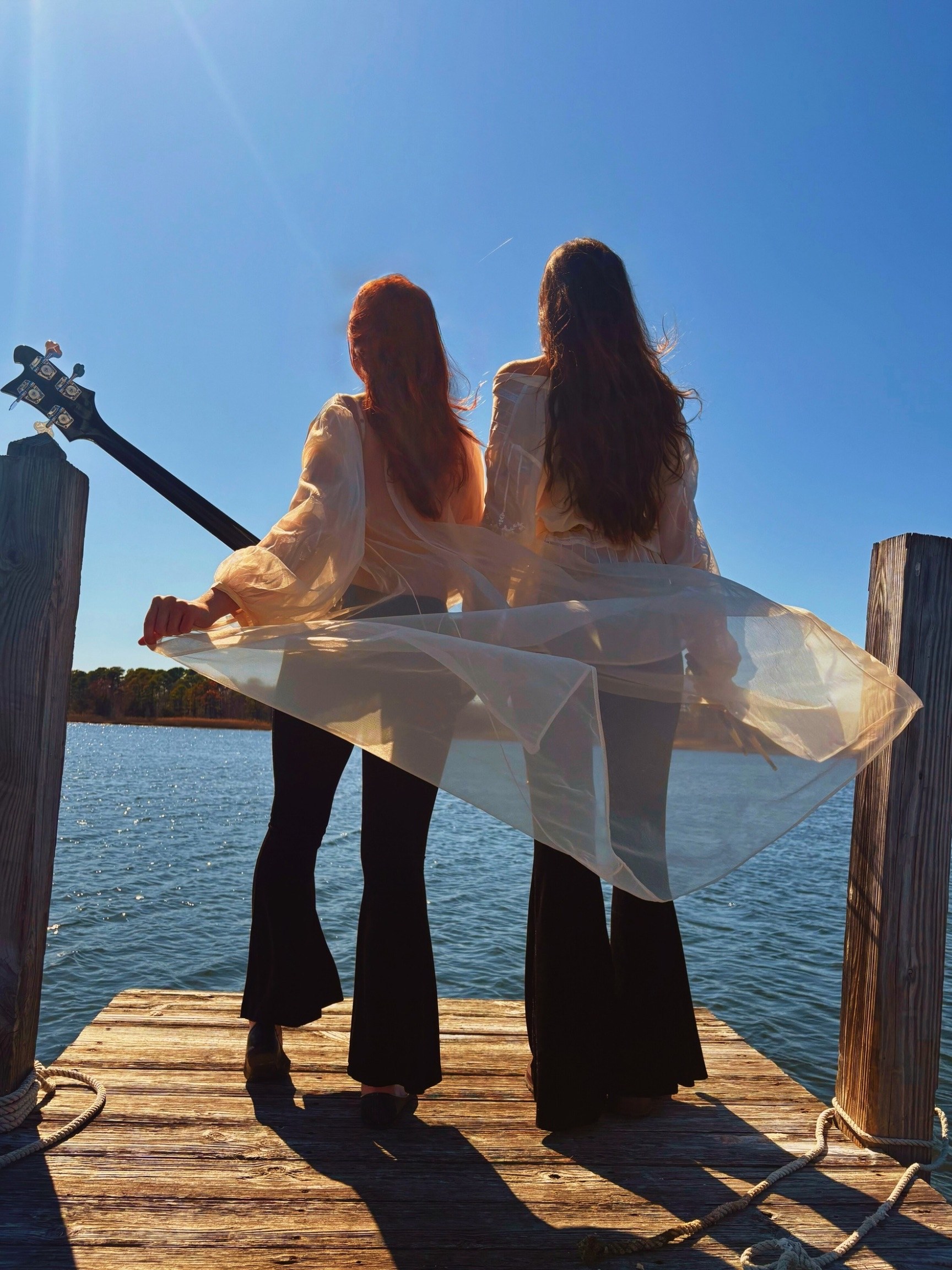 Mónica and Mercedes on the dock, backs to the camera, looking out over the water