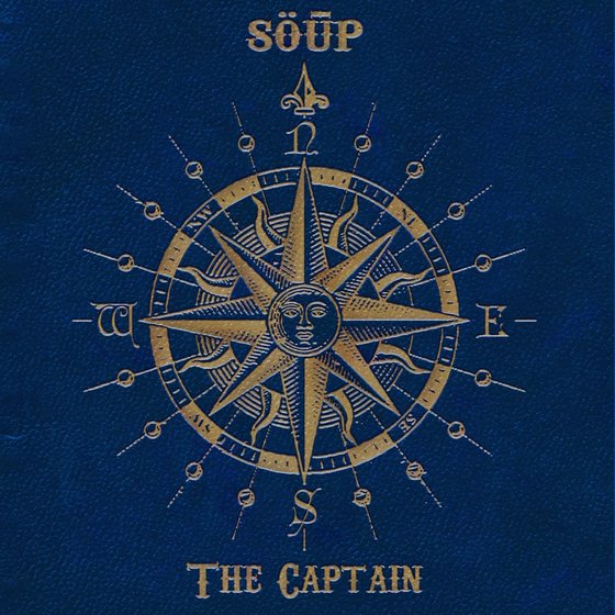 The Captain cover — a gold engraved compass rose with a sun at its centre, on navy cloth