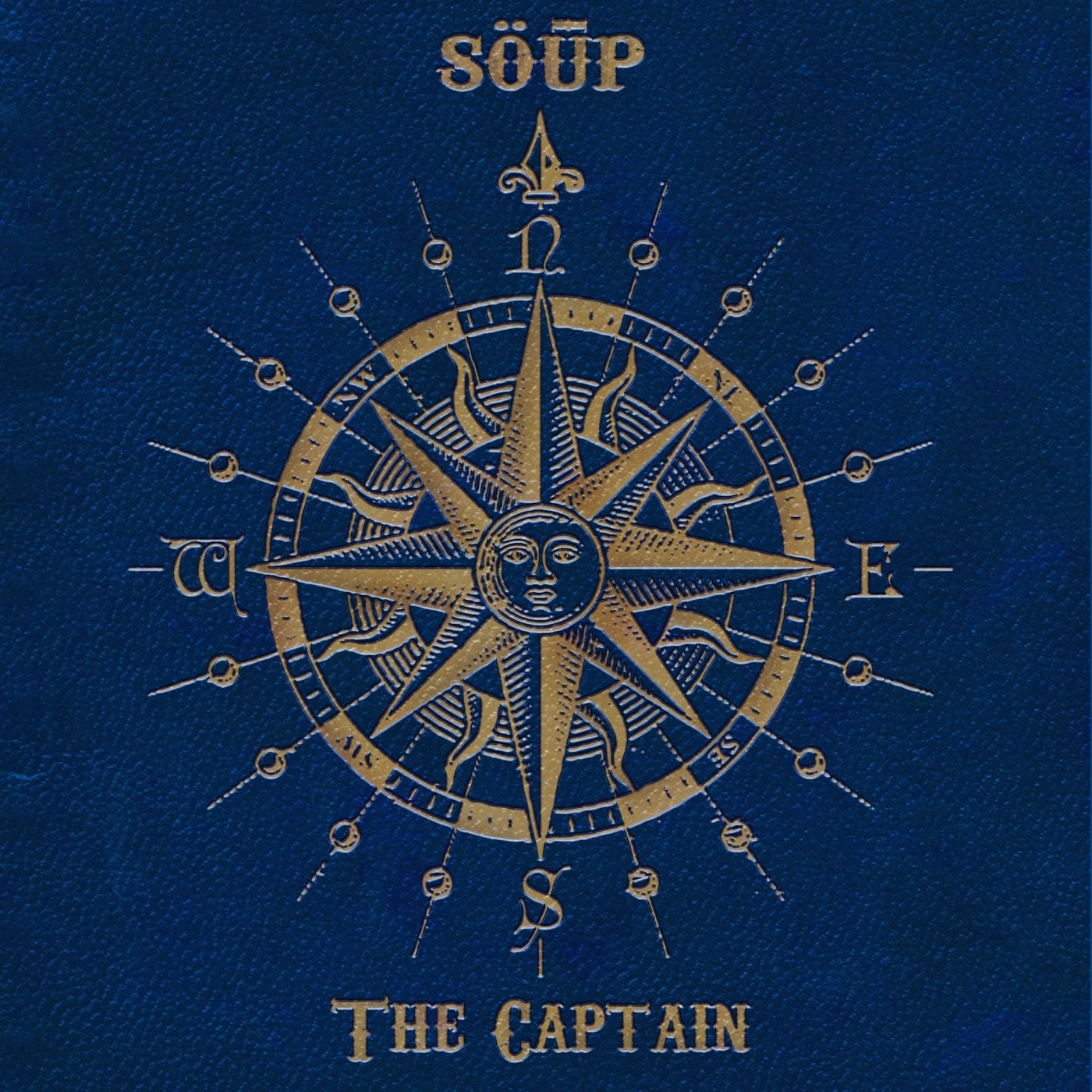 The Captain cover — a gold engraved compass rose with a sun at its centre, on navy cloth
