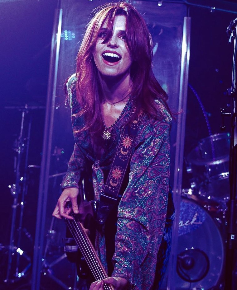 Mercedes of Söūp mid-song with her bass, lit purple